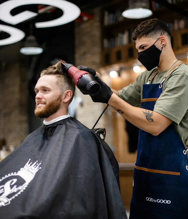 Barbiere che asciuga e modella i capelli di un cliente